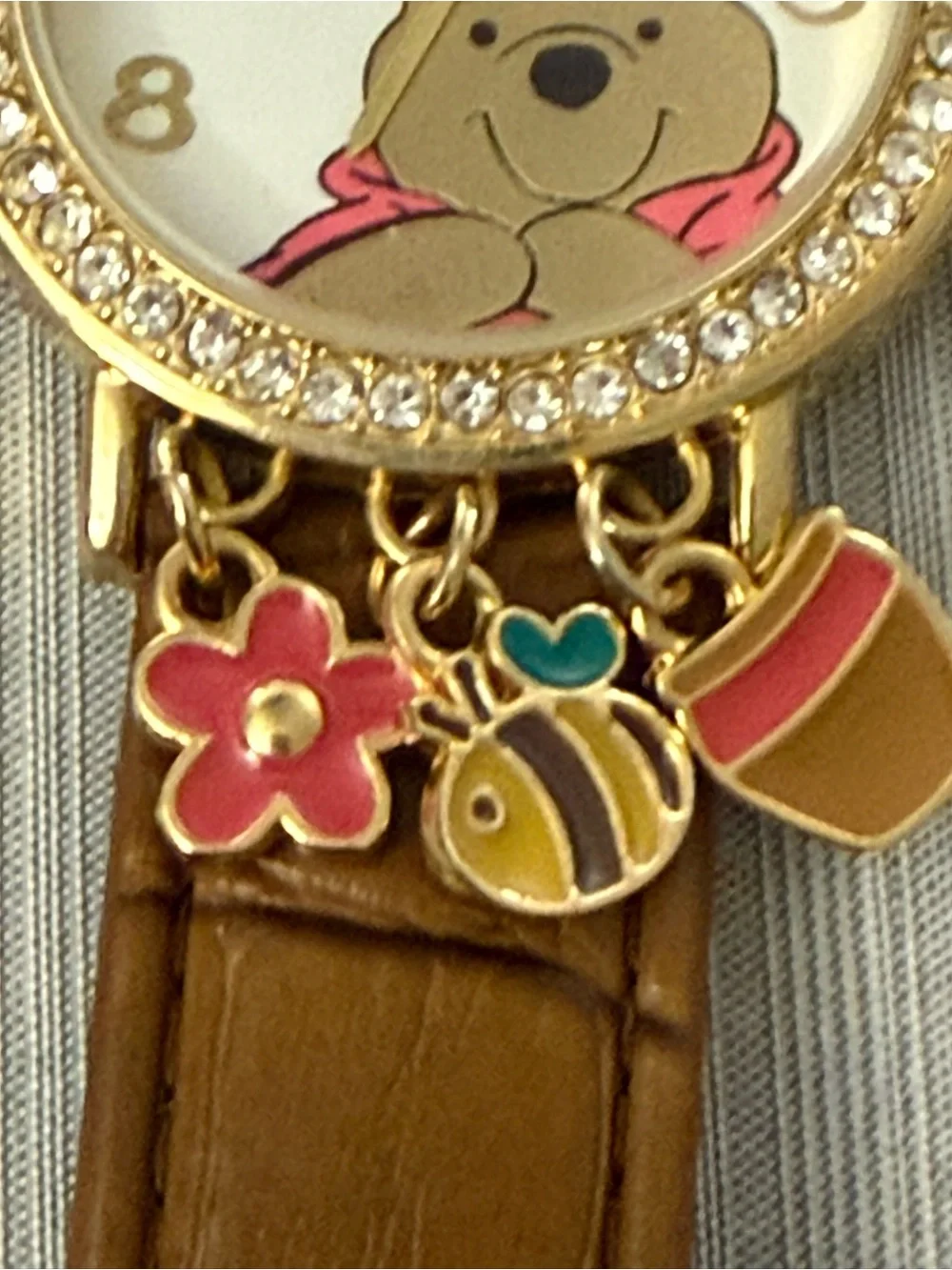 Disney Winnie the Pooh watch features a crystal-bezel dial and dangling charms o